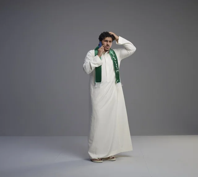 شاب سعودي بالثوب يتحدث بالهاتف الذكي في استوديو