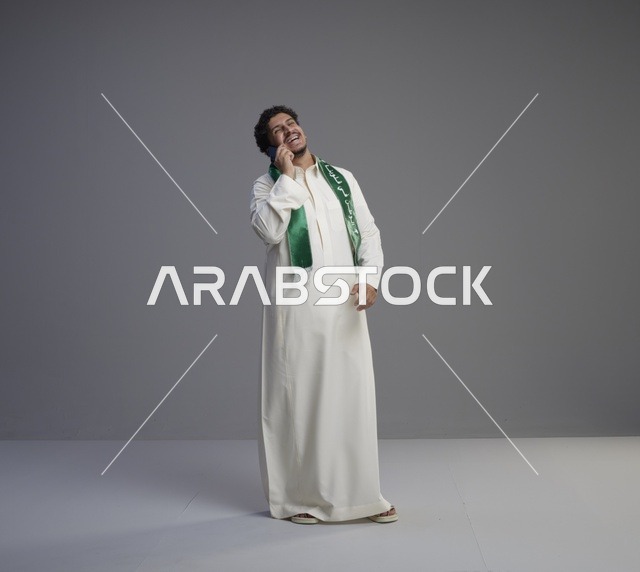شاب سعودي بالثوب يتحدث بالهاتف الذكي في الاستوديو