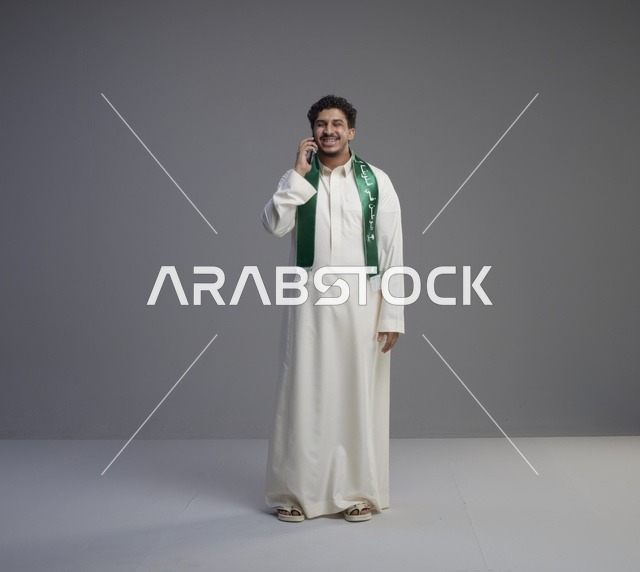 شاب سعودي يتحدث بالهاتف الذكي بالثوب التقليدي