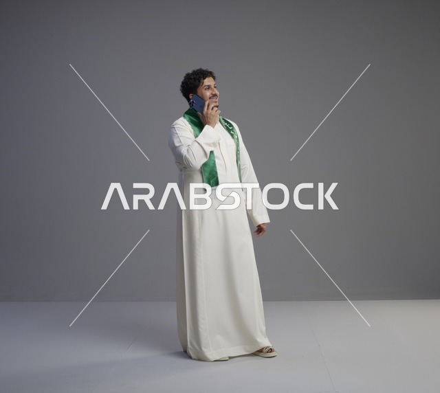 شاب سعودي بالثوب يتحدث عبر الهاتف الذكي في الاستوديو