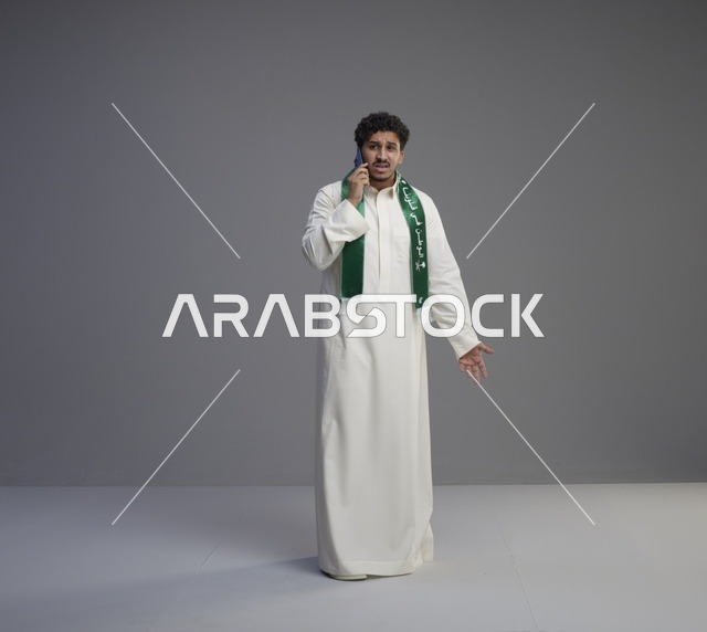 شاب سعودي يتحدث بالهاتف الجوال بالثوب التقليدي