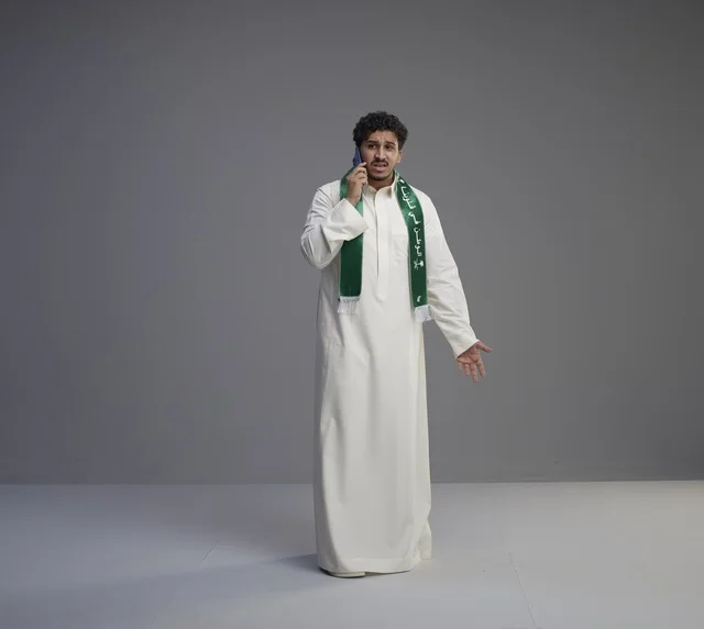 شاب سعودي يتحدث بالهاتف الجوال بالثوب التقليدي