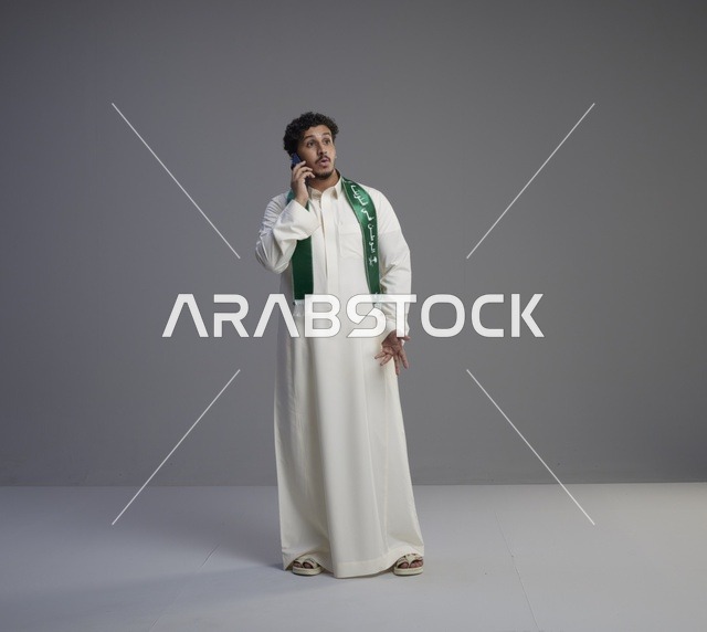 شاب سعودي بالثوب التقليدي يتحدث عبر الجوال في استوديو
