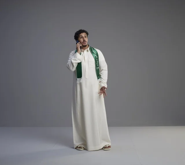 شاب سعودي بالثوب التقليدي يتحدث عبر الجوال في استوديو