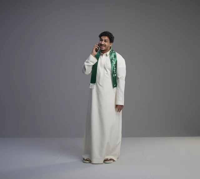 شاب سعودي بالثوب يتحدث عبر الهاتف الذكي في الاستوديو