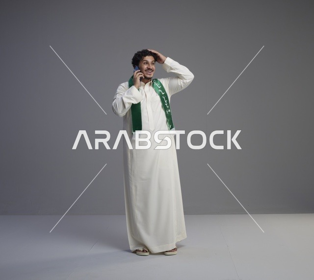 شاب سعودي يتحدث بالجوال في الاستوديو بالزي التقليدي