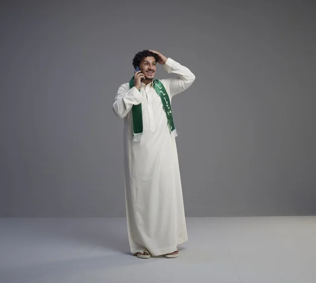 شاب سعودي يتحدث بالجوال في الاستوديو بالزي التقليدي