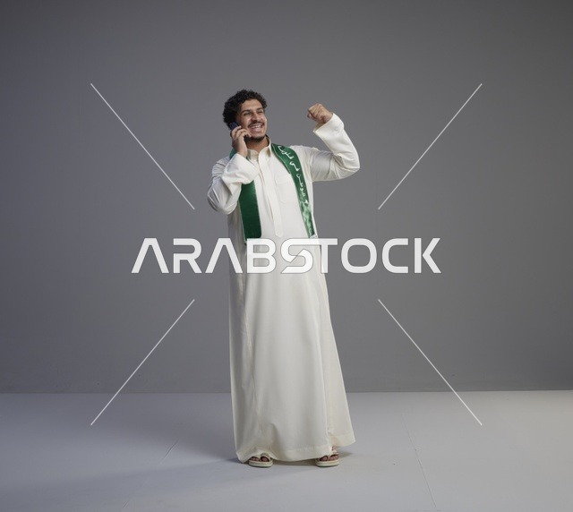 شاب سعودي يتحدث بالهاتف ويحتفل بالثوب التقليدي