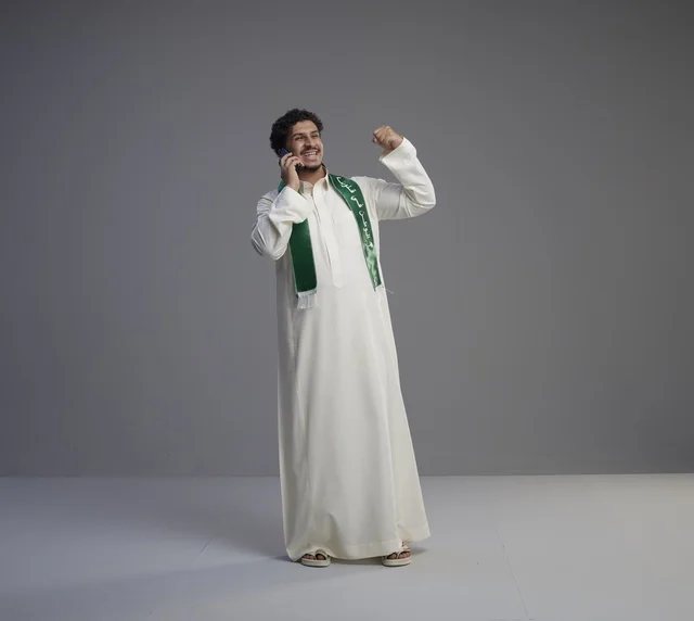 شاب سعودي يتحدث بالهاتف ويحتفل بالثوب التقليدي