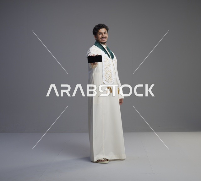 شاب سعودي يحمل هاتف ذكي بشاشة سوداء فارغة