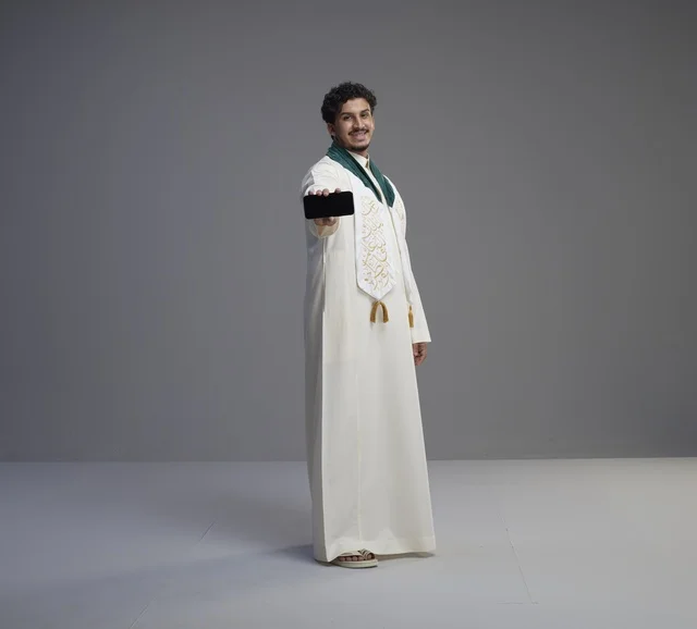 شاب سعودي يحمل هاتف ذكي بشاشة سوداء فارغة