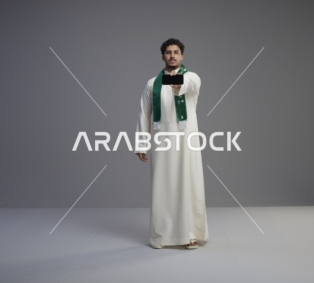شاب سعودي يحمل هاتف ذكي بشاشة فارغة