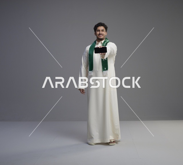 شاب سعودي يحمل هاتف ذكي بشاشة فارغة