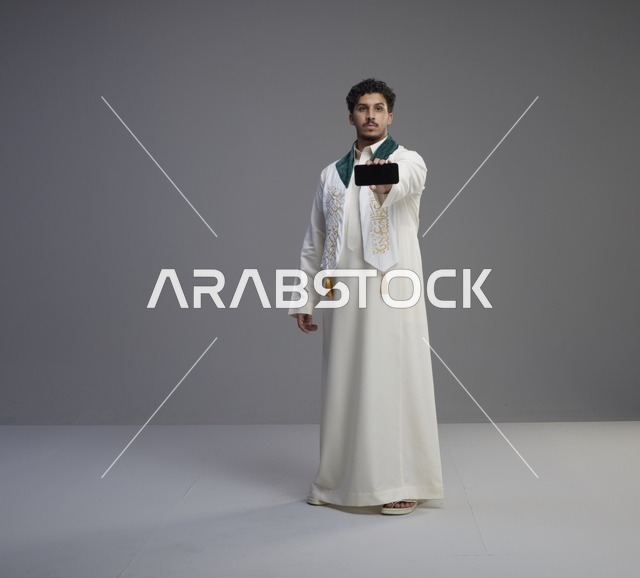 شاب سعودي يمسك هاتف ذكي بشاشة فارغة
