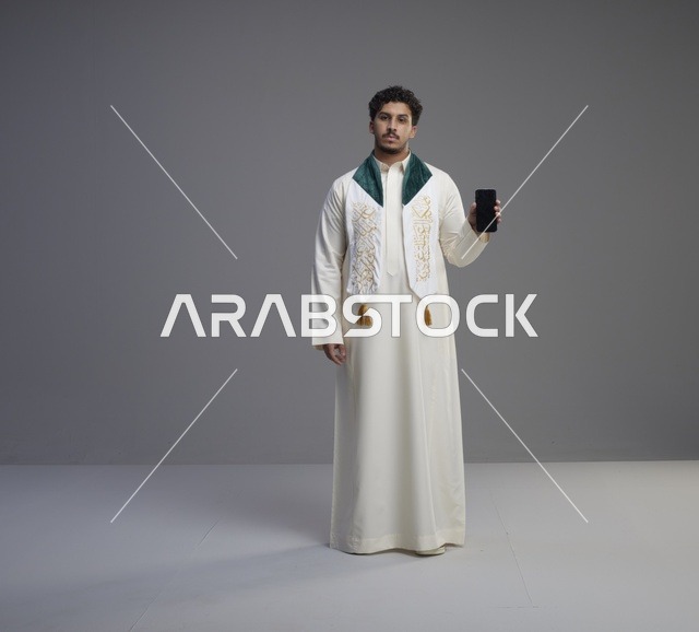 شاب سعودي يحمل هاتف ذكي بشاشة فارغة
