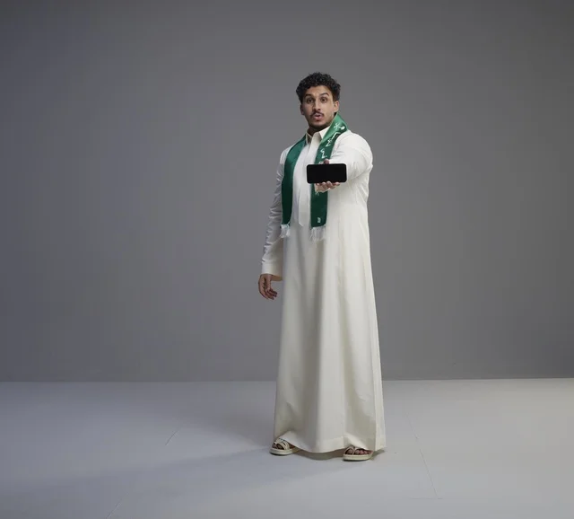 Saudi Man in Traditional Thobe Holding Smartphone Screen
