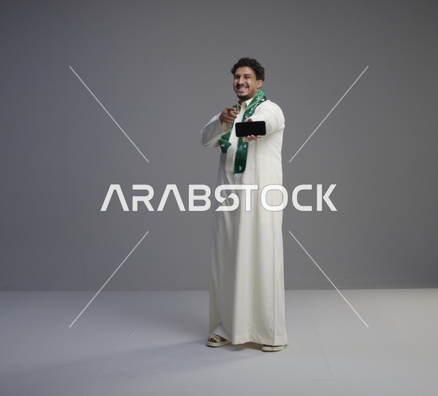 شاب سعودي يحمل هاتف ذكي بشاشة فارغة في استوديو