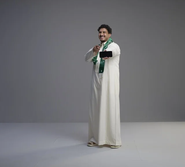 Saudi Man Holding Smartphone with Blank Screen in Studio