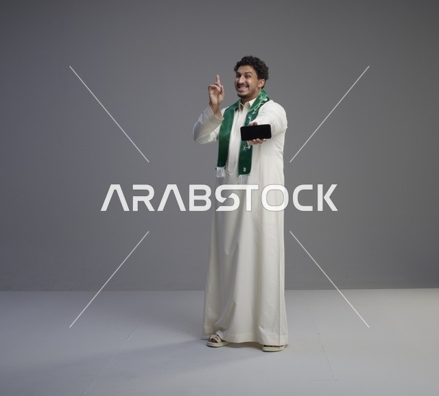 شاب سعودي يحمل هاتف ذكي بوشاح أخضر