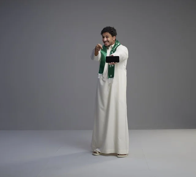 Saudi Man Holding Smartphone in Studio Grey Background
