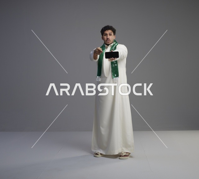 شاب سعودي يحمل هاتف ذكي بشاشة فارغة