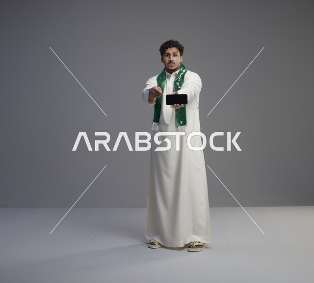 شاب سعودي يعرض شاشة هاتف ذكي في استوديو