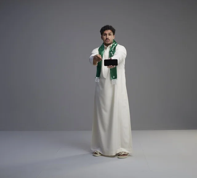 شاب سعودي يعرض شاشة هاتف ذكي في استوديو