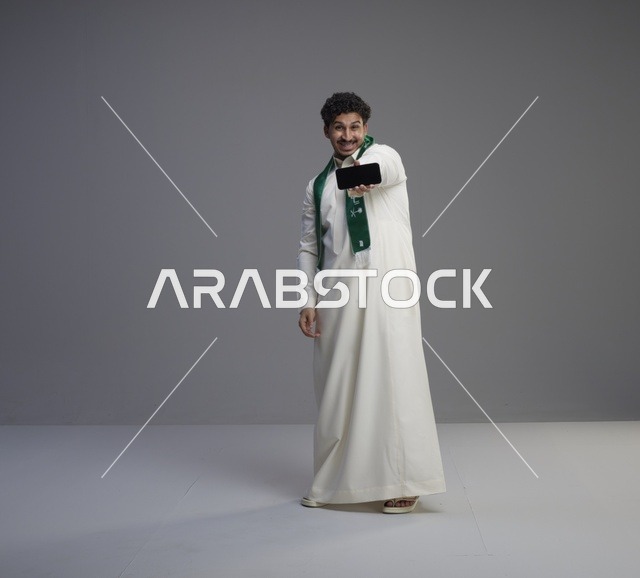 شاب سعودي يحمل هاتف ذكي بشاشة فارغة