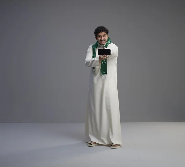 Saudi Man in Thobe Holding Smartphone with Blank Screen