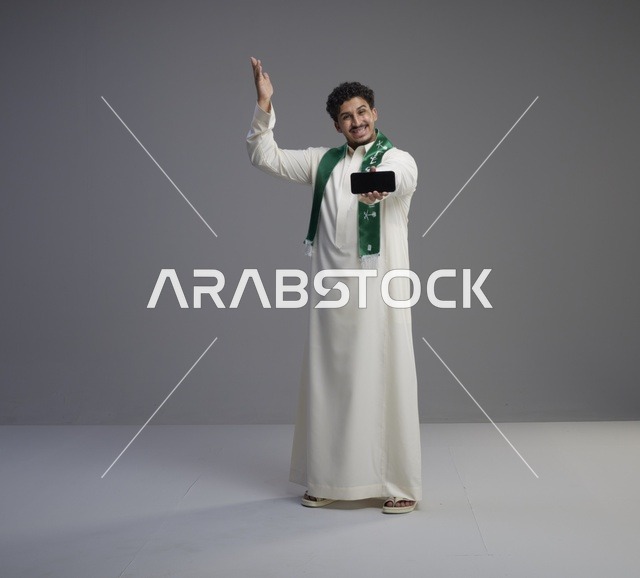شاب سعودي يحمل هاتف ذكي بشاشة فارغة