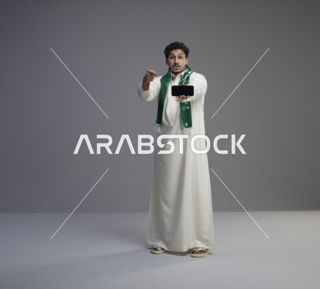 شاب سعودي يحمل هاتف ذكي في استوديو