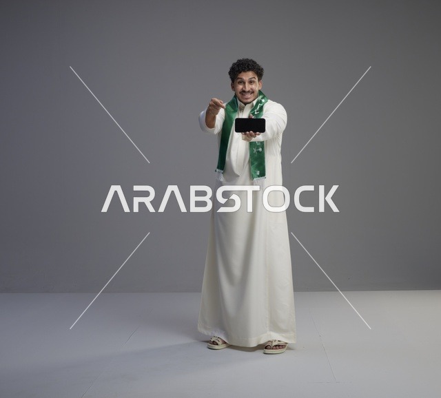 شاب سعودي يحمل هاتف ذكي بشاشة فارغة