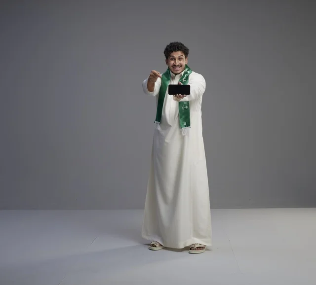 شاب سعودي يحمل هاتف ذكي بشاشة فارغة