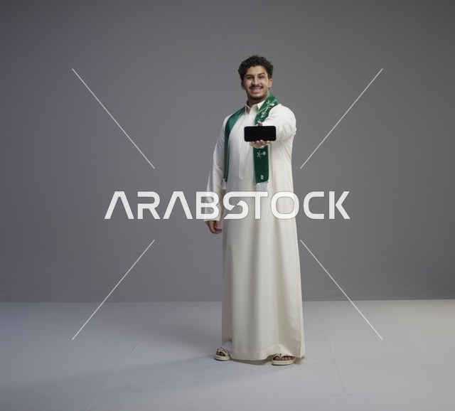 شاب سعودي يحمل هاتف ذكي بشاشة أفقية فارغة