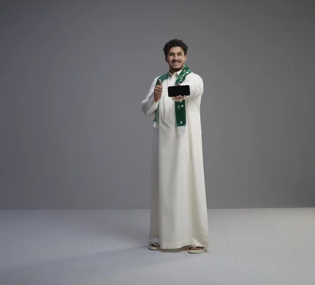 Saudi Man Holding Smartphone with Thumbs Up Gesture