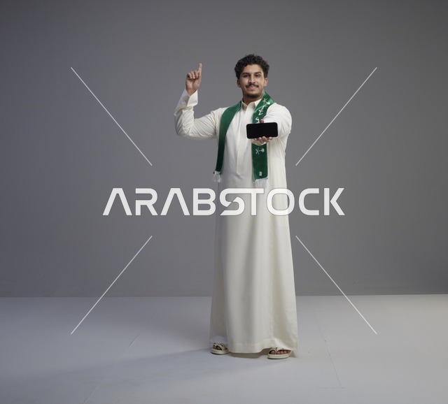 شاب سعودي يحمل هاتفاً ذكياً في الاستوديو