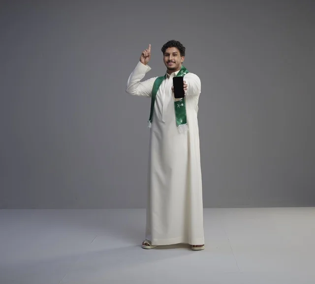 Saudi Man Holding Smartphone Pointing Up in Studio