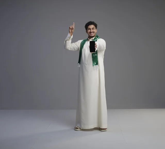 شاب سعودي يمسك هاتف ذكي بشاشة سوداء فارغة