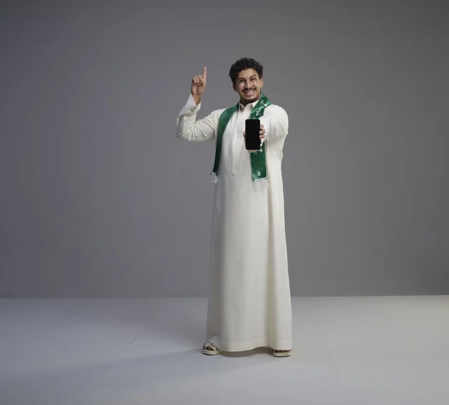 Saudi Man in Thobe Holding Smartphone Screen