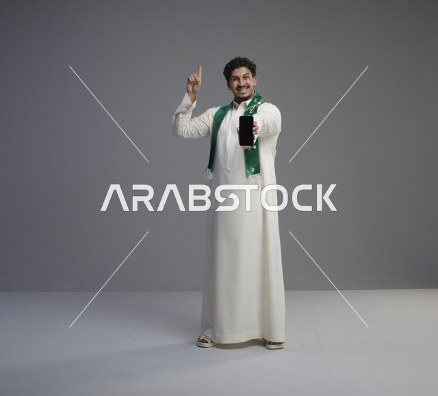 شاب سعودي يحمل هاتف ذكي في الاستوديو