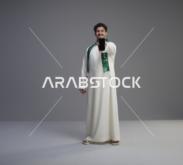 شاب سعودي يحمل هاتف ذكي بشاشة فارغة