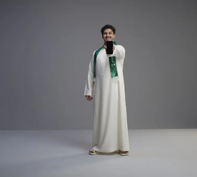 شاب سعودي يحمل هاتف ذكي بشاشة فارغة