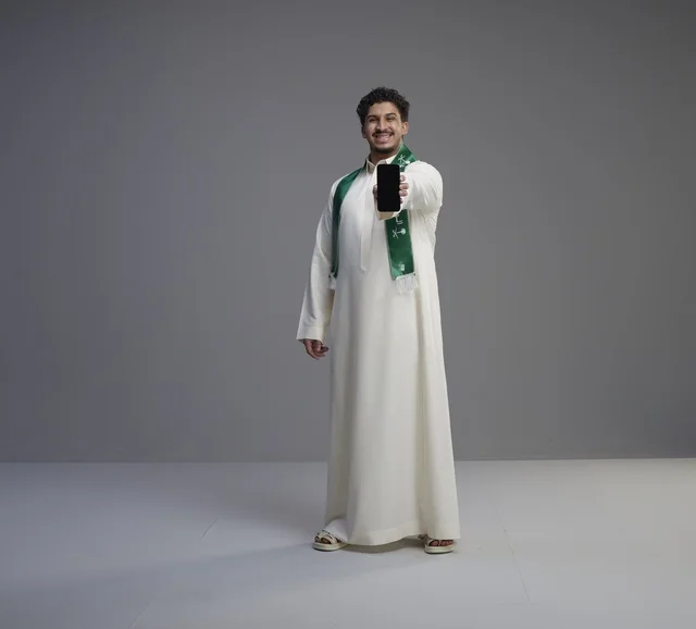 شاب سعودي يحمل هاتف ذكي بشاشة فارغة
