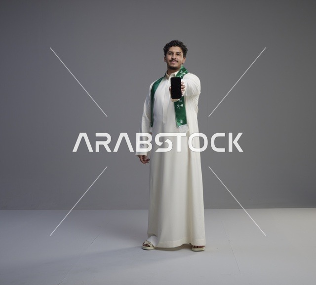 شاب سعودي يحمل هاتف ذكي بشاشة فارغة