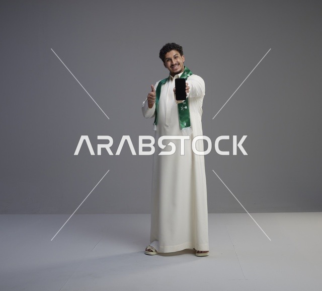شاب سعودي يحمل هاتف ذكي مع علامة الإعجاب بالاستوديو