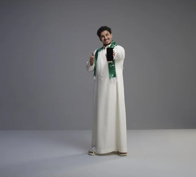 شاب سعودي يحمل هاتف ذكي مع علامة الإعجاب بالاستوديو