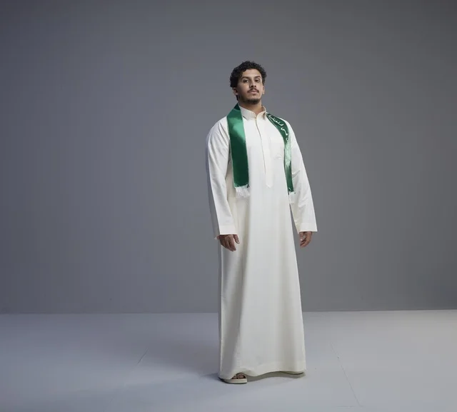 شاب سعودي بالثوب والوشاح الوطني الأخضر في الاستوديو