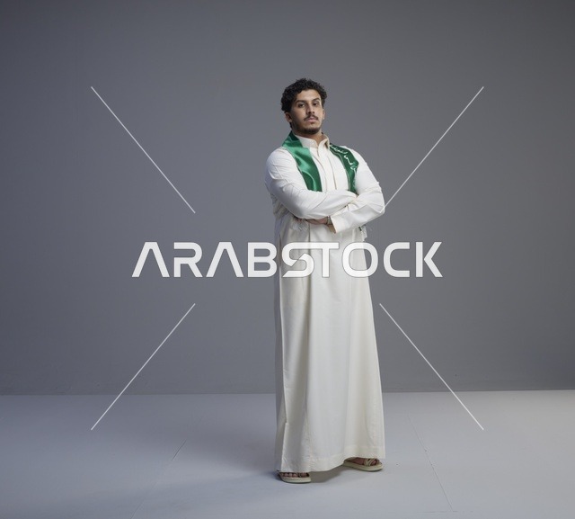 شاب سعودي بالثوب التقليدي والوشاح الوطني في الاستوديو