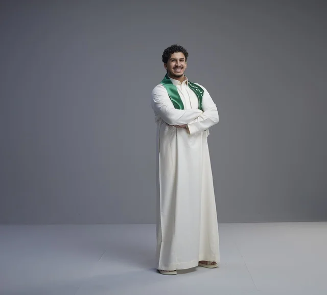 شاب سعودي يرتدي الوشاح الوطني في استوديو تصوير