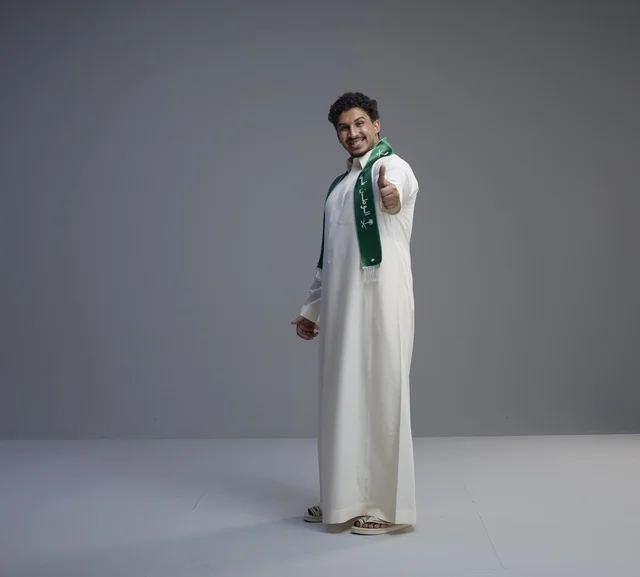 شاب سعودي بالوشاح الوطني وعلامة الإبهام للأعلى